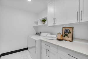 Laundry area featuring white cabinetry, light-toned countertops, and built-in shelving