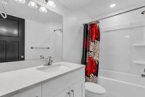 Bathroom featuring a white vanity with an integrated sink, polished chrome faucet, a large wall-mounted mirror, and a shower-tub combination with white surround