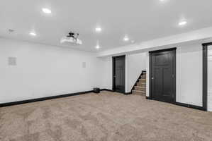 Spacious room featuring an installed ceiling projector, in-wall speakers, recessed lighting, and dark trim details