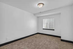 Neutral toned carpeted room featuring a white ceiling and walls with dark baseboards