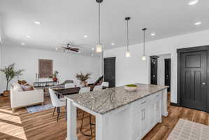 Central kitchen island with a granite countertop, white cabinetry, and pendant lighting