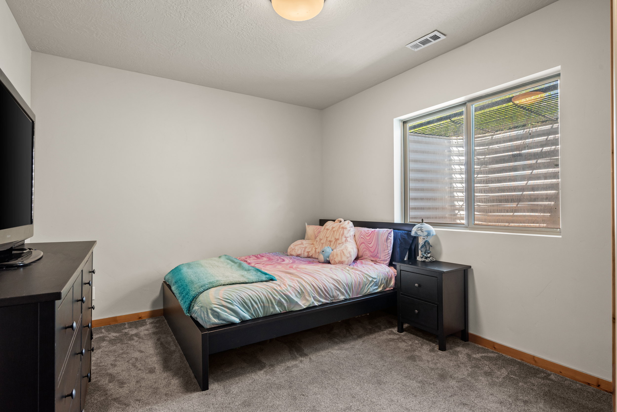 Bedroom featuring a large egress window, neutral wall paint, and gray carpet flooring