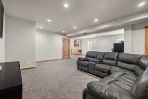 Spacious entertainment area with recessed lighting, light gray carpeting, and light-toned walls