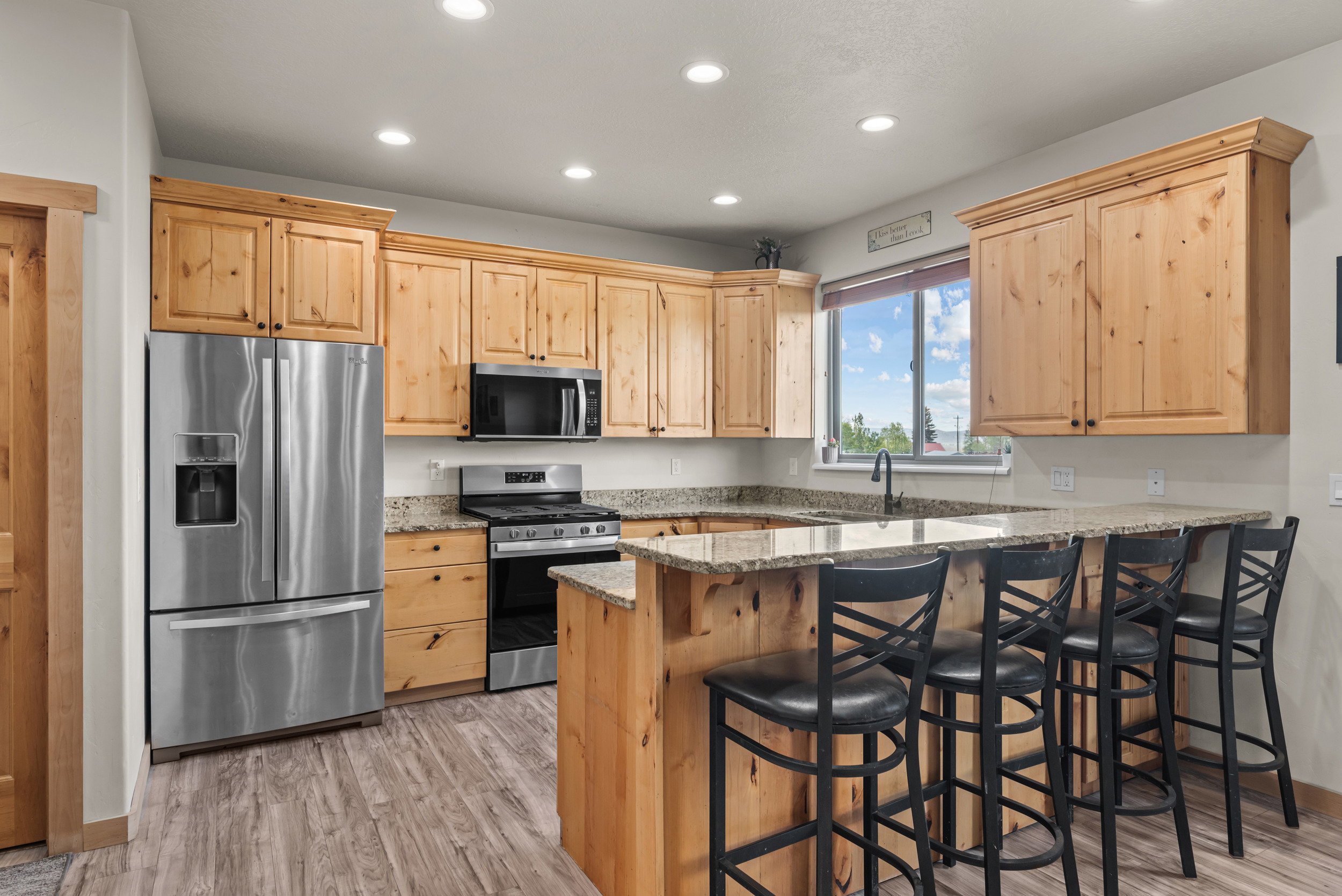 Kitchen featuring extensive light wood cabinetry, stainless steel appliances, granite countertops, wood-finish flooring, and recessed lighting