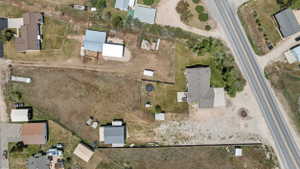Expansive property featuring a main residence with a gray shingle roof, a secondary structure with a light gray roof, and a large open land area