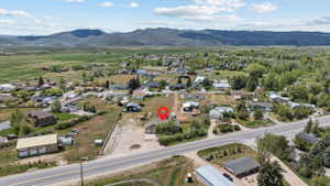 Expansive lot with a single-story residence and detached garage, featuring a paved driveway and surrounding natural landscape