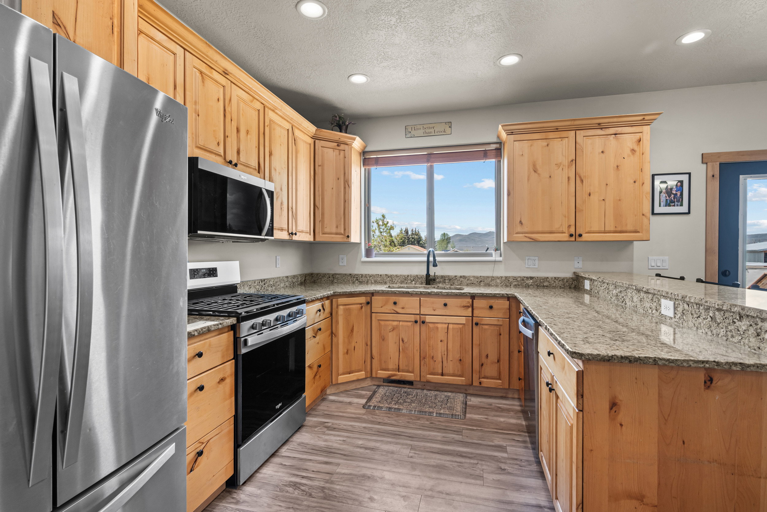Kitchen featuring light wood cabinetry, granite countertops, stainless steel appliances, wood-finish flooring, and recessed lighting