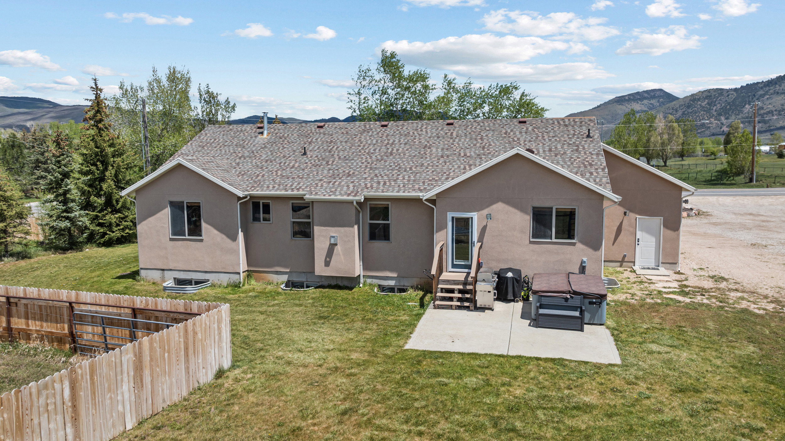 Rear exterior of a stucco residence featuring a shingle roof