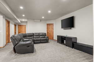 Recessed lighting illuminates a spacious room featuring light gray carpeting and white walls