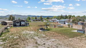 Expansive property featuring a large metal carport, a separate shed, a fenced perimeter, a concrete patio, and a hot tub