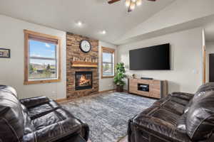 Living room featuring a stone-clad fireplace with a wood mantle, vaulted ceilings, recessed lighting, and wood-finish flooring