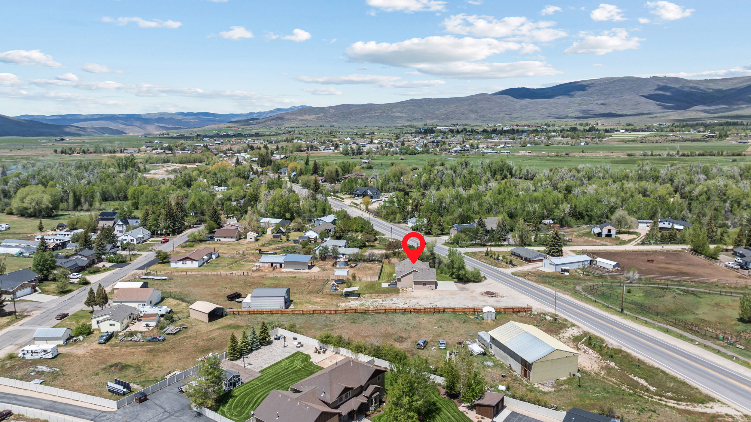Aerial perspective showcasing the property's position within a residential area, surrounded by expansive green landscapes and distant mountains