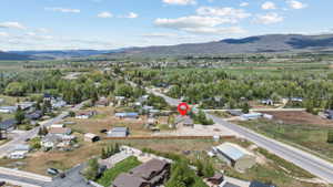 Aerial perspective showcasing the property's position within a residential area, surrounded by expansive green landscapes and distant mountains