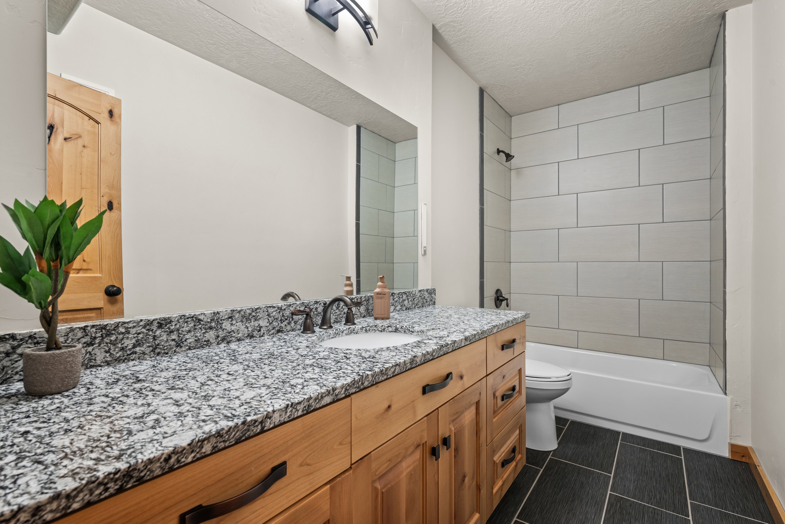 Bathroom featuring a wood-finish vanity with an integrated sink and a speckled countertop