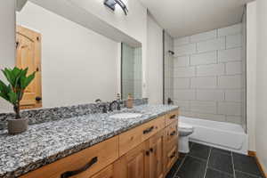 Bathroom featuring a wood-finish vanity with an integrated sink and a speckled countertop