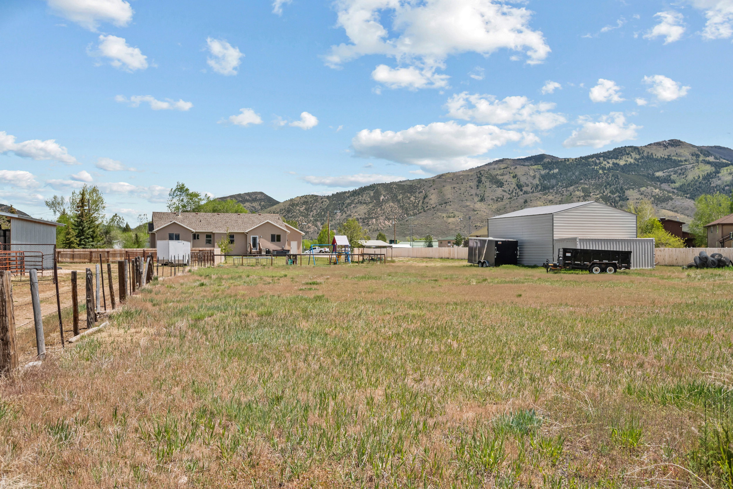 Expansive grassy yard with a wooden fence and mountain backdrop
