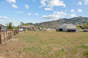 Expansive grassy yard with a wooden fence and mountain backdrop