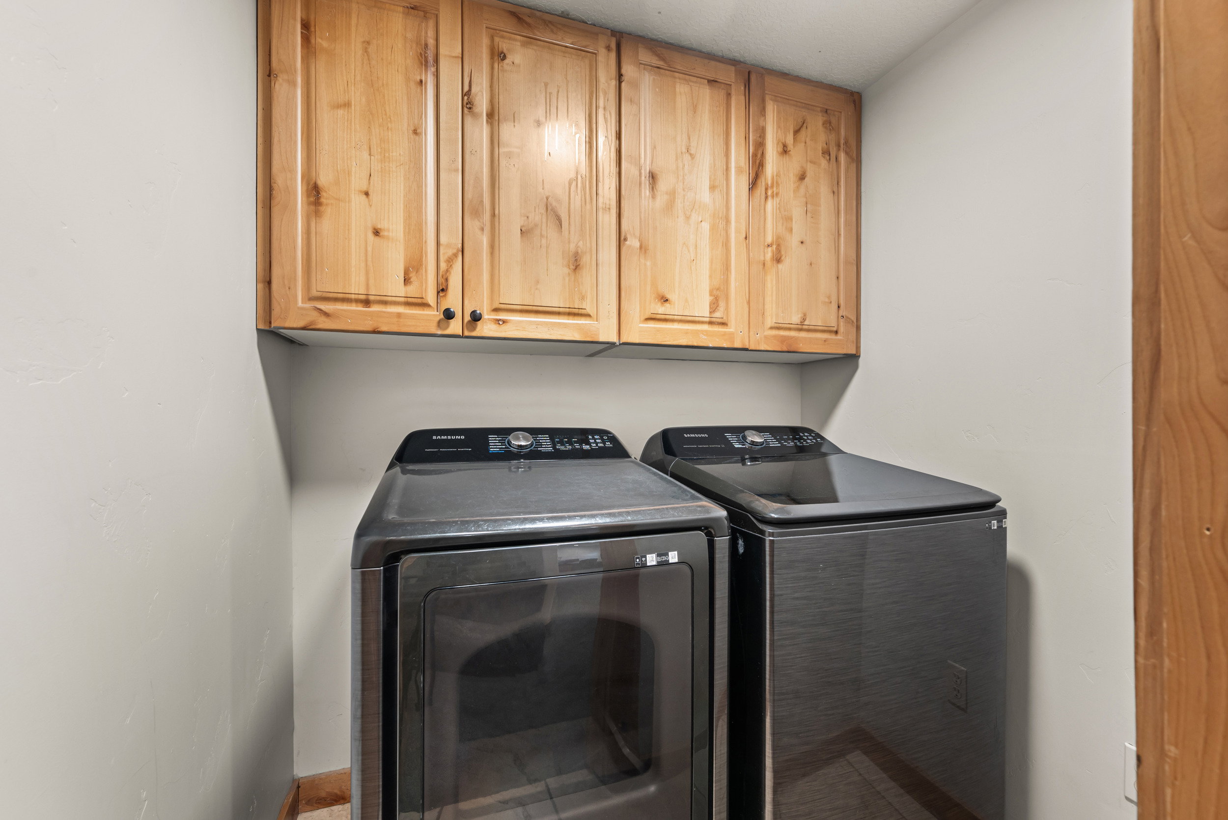 Laundry area featuring light wood cabinetry, neutral painted walls, and wood-finish flooring