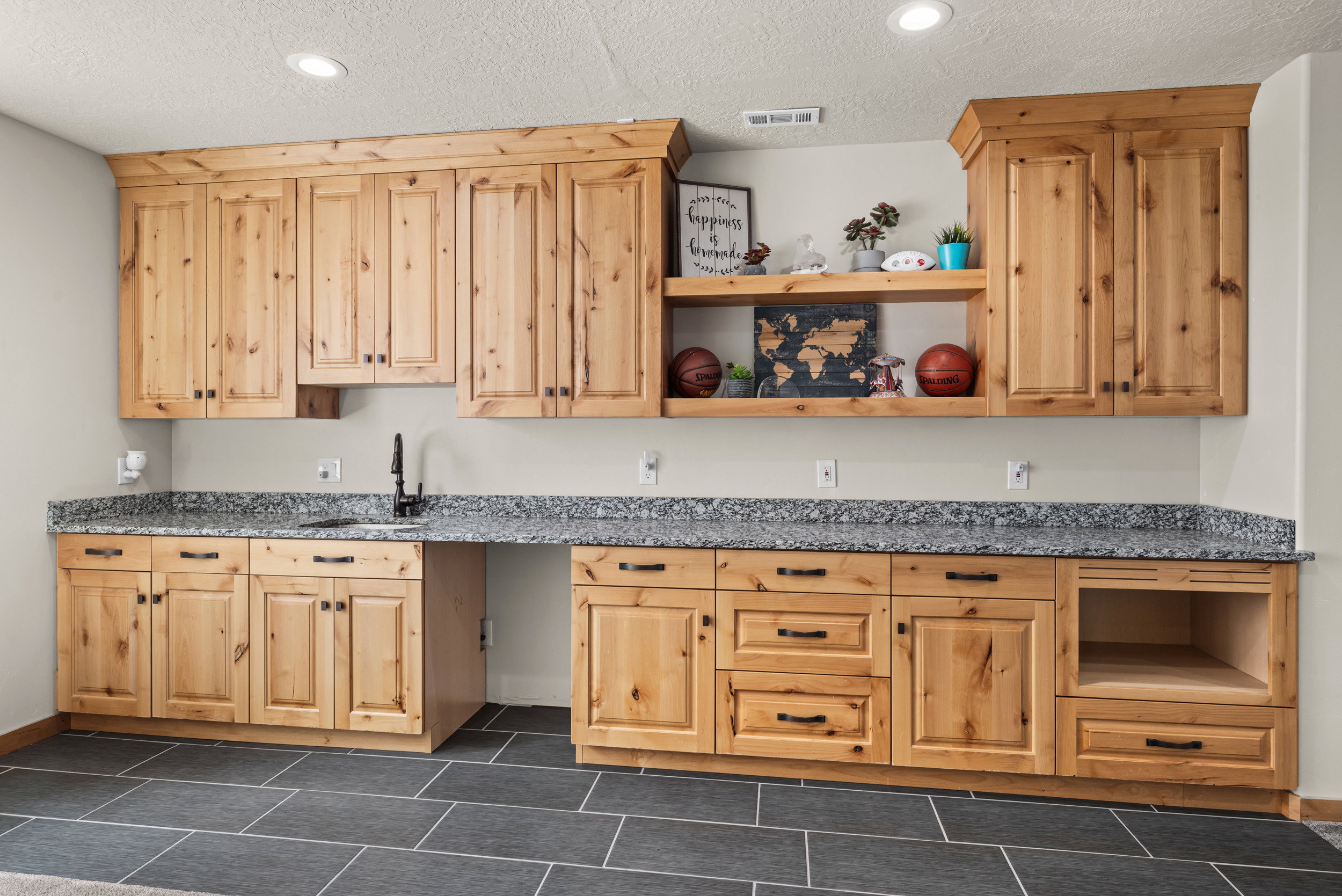 Extensive built-in cabinetry with natural wood-finish, featuring a black countertop with an integrated sink and black faucet