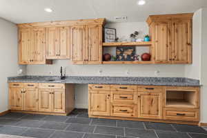 Extensive built-in cabinetry with natural wood-finish, featuring a black countertop with an integrated sink and black faucet