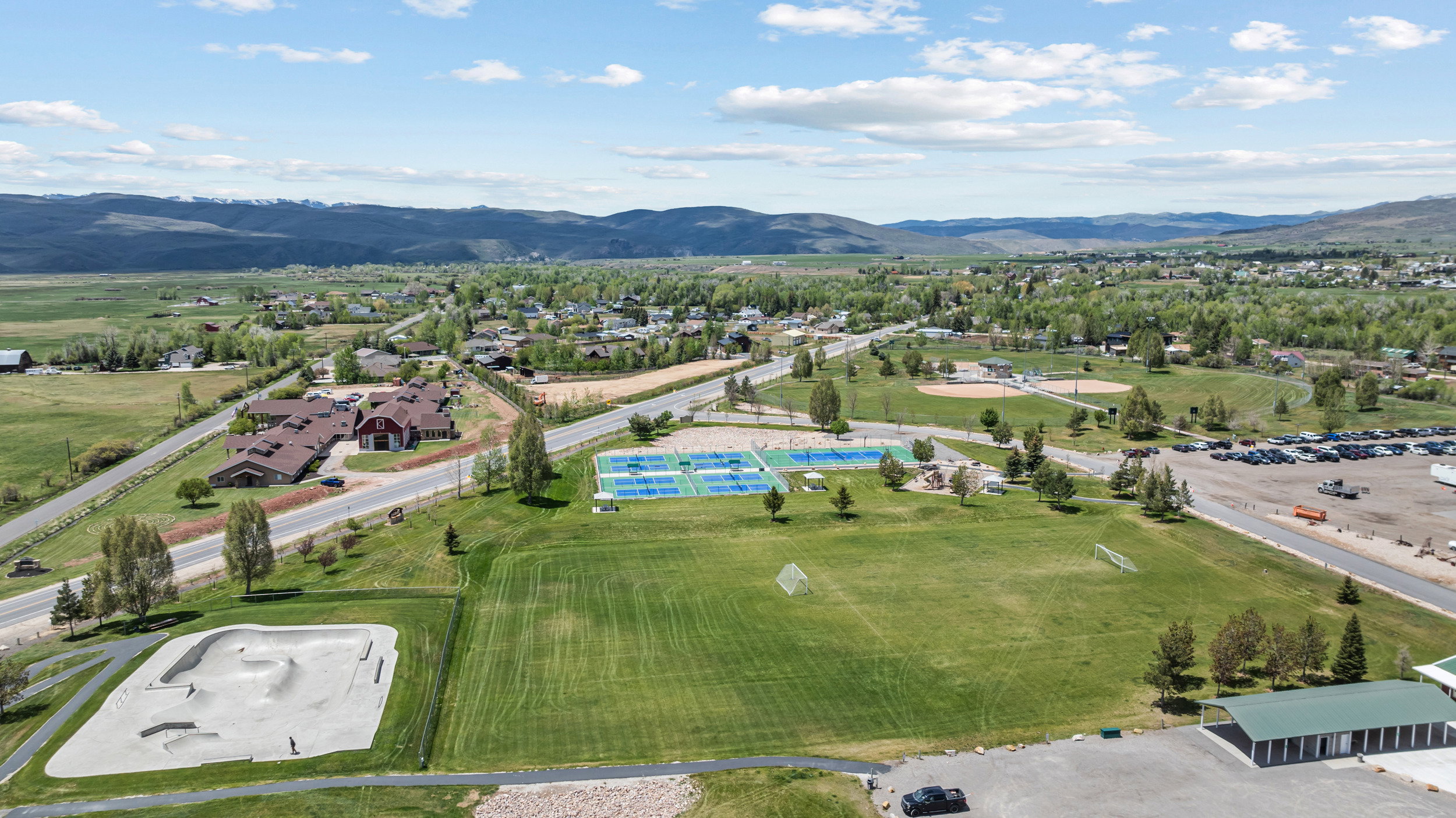 Expansive green spaces featuring multiple sports courts, a baseball field, and a skate park