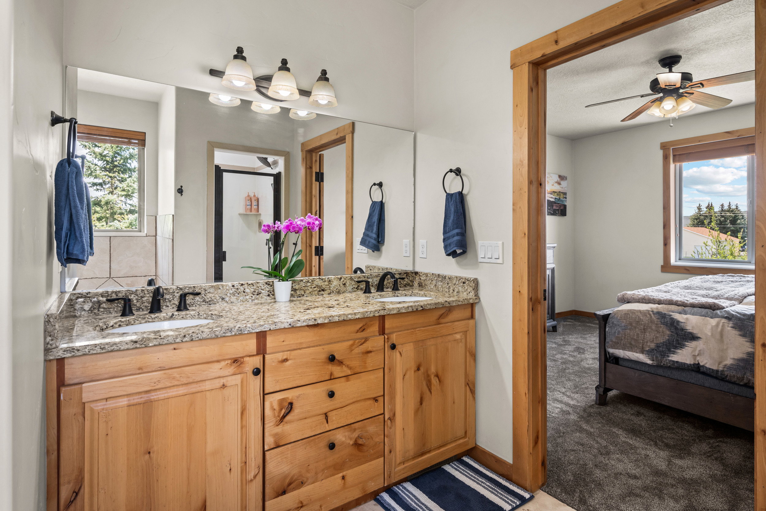 Bathroom vanity featuring dual sinks, granite countertop, and wood cabinetry
