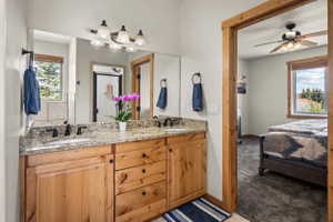 Bathroom vanity featuring dual sinks, granite countertop, and wood cabinetry