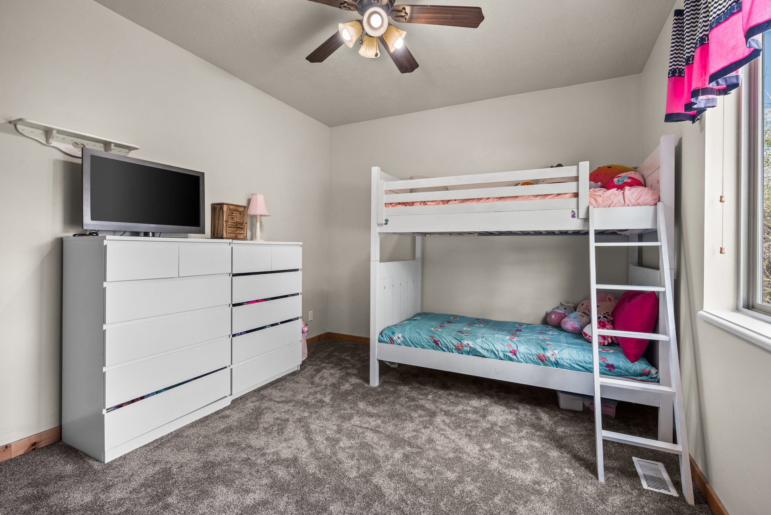 Carpeted room with a ceiling fan, baseboard trim, and a window providing natural light