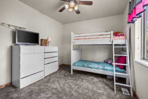 Carpeted room with a ceiling fan, baseboard trim, and a window providing natural light
