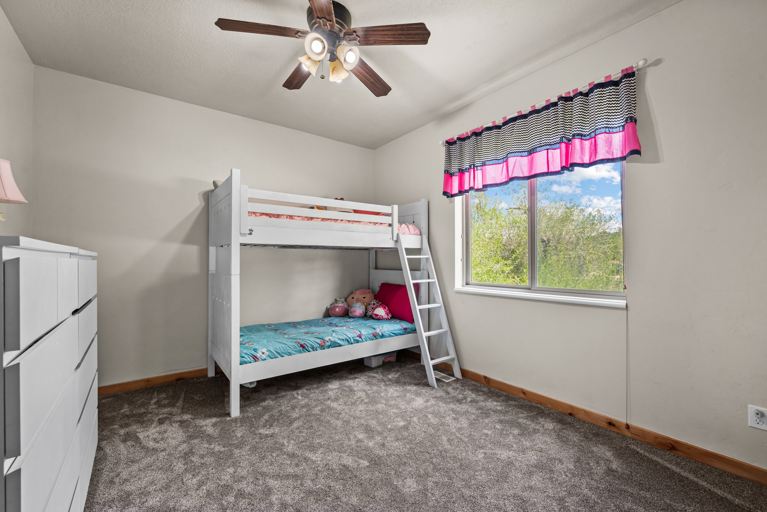 Bedroom featuring gray carpet flooring, light neutral wall paint, and a window offering natural light