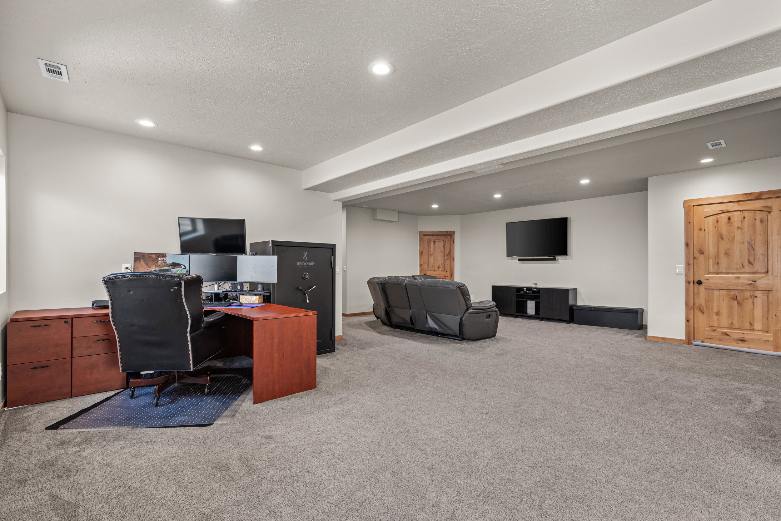 Spacious room featuring gray carpeting, recessed ceiling lighting, and light wood-grain doors