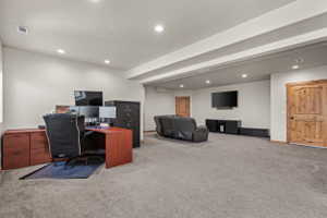 Spacious room featuring gray carpeting, recessed ceiling lighting, and light wood-grain doors