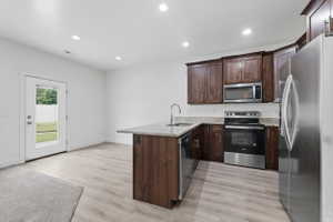 Kitchen area featuring dark wood-finish cabinetry, stainless steel appliances, and light-toned countertop surfaces