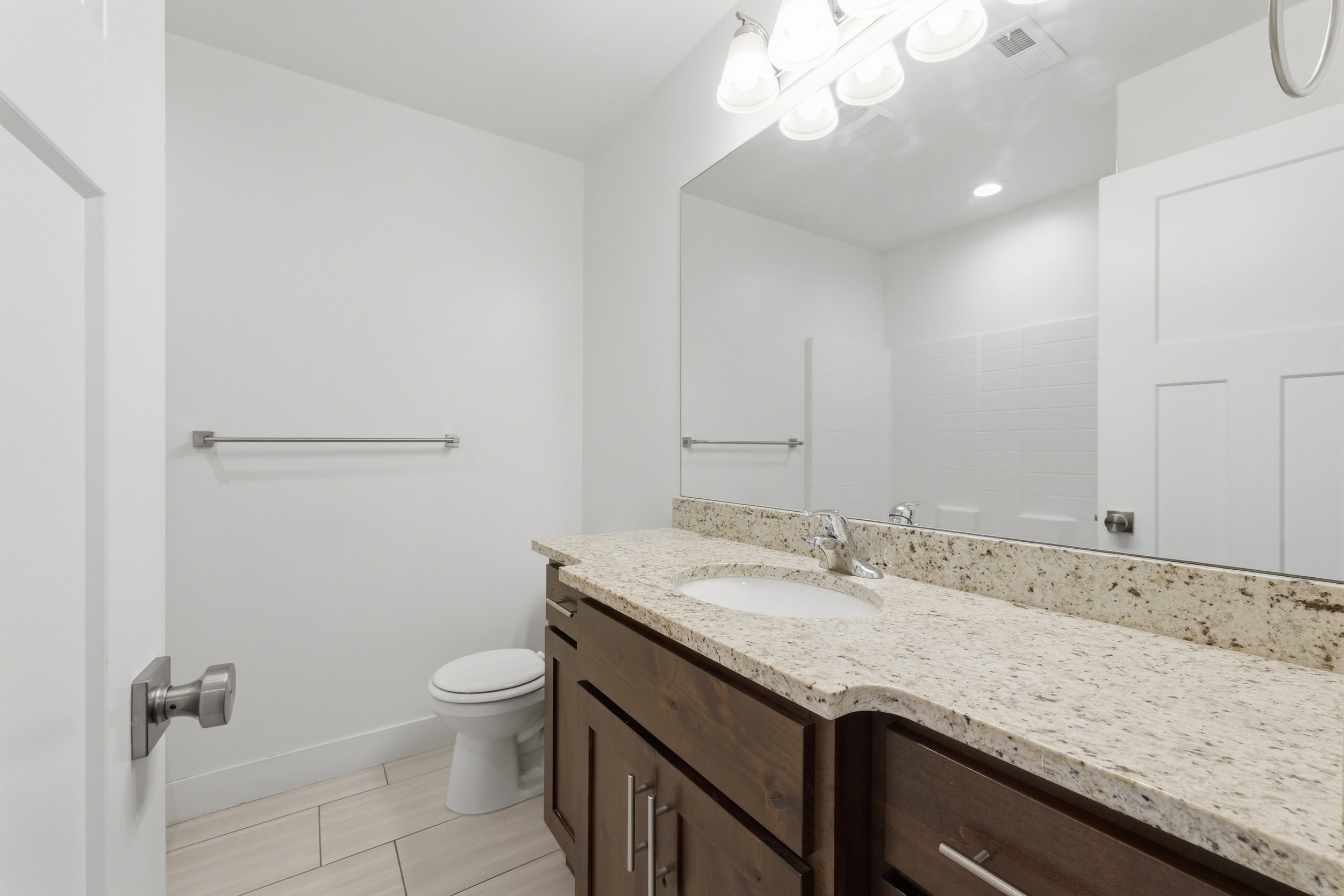 Bathroom featuring a wood-finish vanity with a light-toned countertop, a rectangular sink, and a large mirror