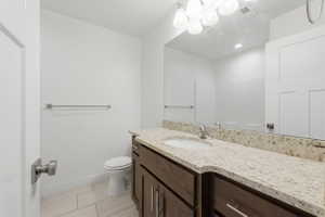 Bathroom featuring a wood-finish vanity with a light-toned countertop, a rectangular sink, and a large mirror