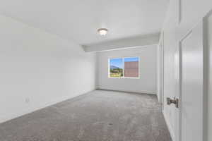 Spacious room with plush gray carpeting, white walls, and a large window offering natural light