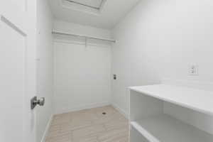 Bright utility space featuring light-toned wood-finish flooring, white walls, and built-in shelving