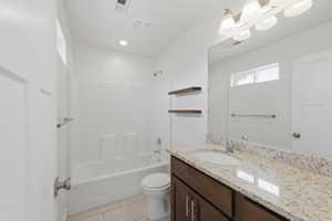 Bathroom featuring a vanity with a light granite countertop and undermount sink, dark wood-finish cabinetry, a full-width mirror, and a shower-tub combination with white subway tile surround