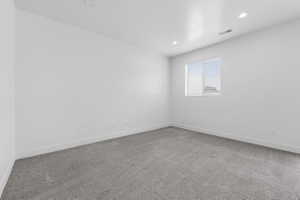 Room featuring neutral gray carpeting, white walls, recessed ceiling lighting, a single window with blinds, and white baseboards