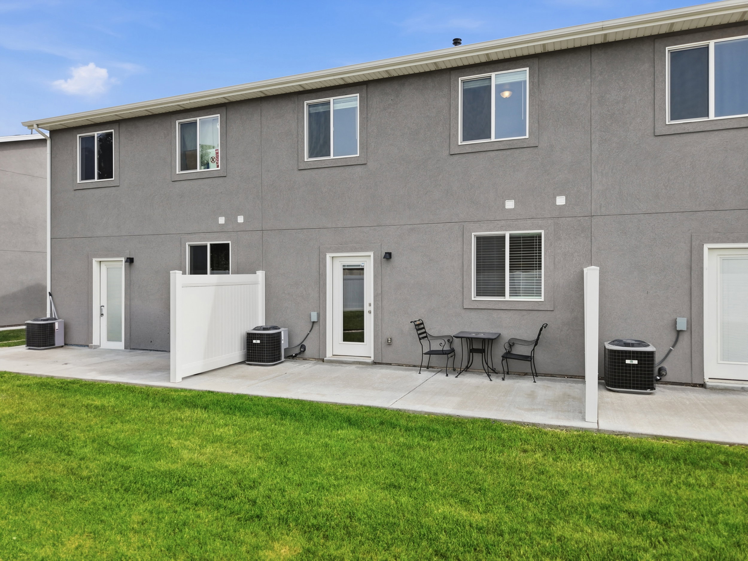 Exterior patio area featuring a concrete slab, a partial privacy fence, and a vibrant green lawn