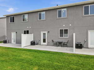 Exterior patio area featuring a concrete slab, a partial privacy fence, and a vibrant green lawn