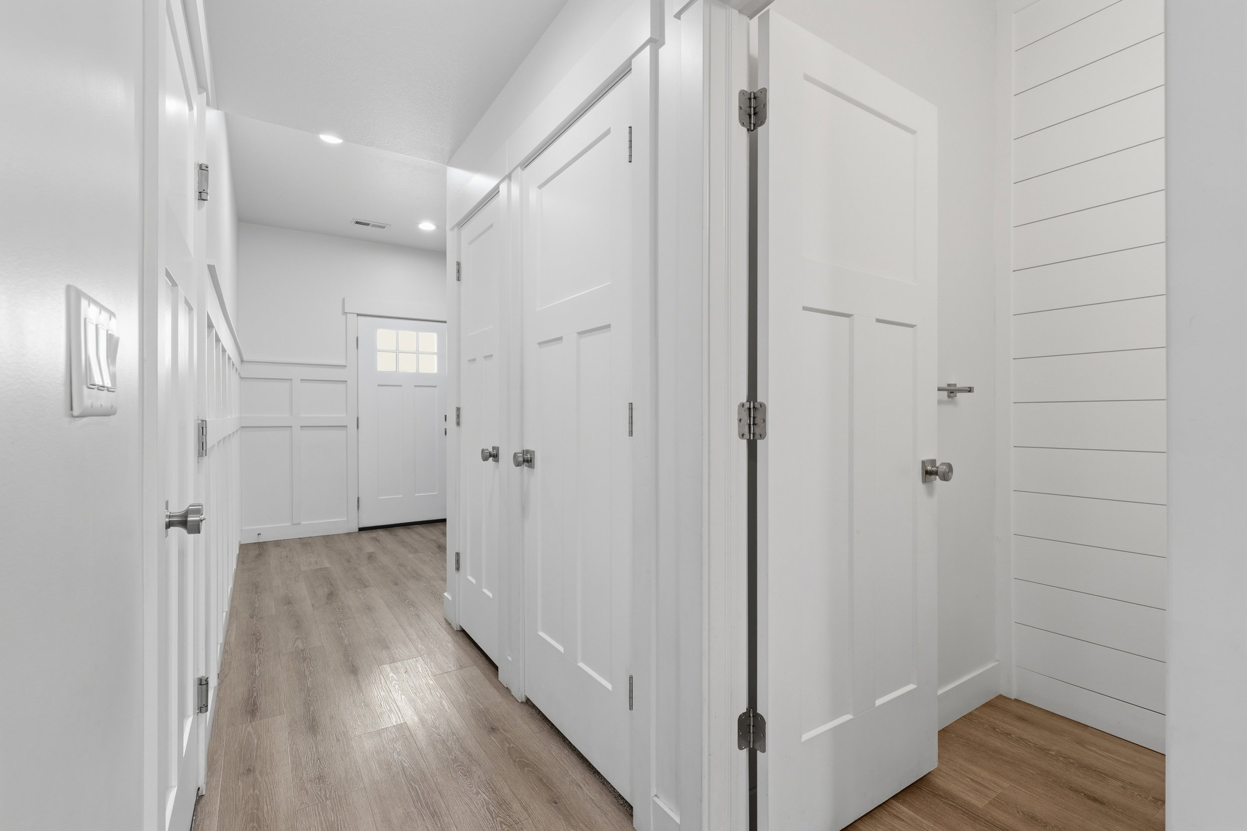 Hallway featuring wood-finish flooring, recessed lighting, and white paneled doors