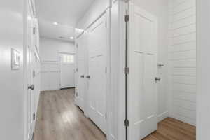 Hallway featuring wood-finish flooring, recessed lighting, and white paneled doors