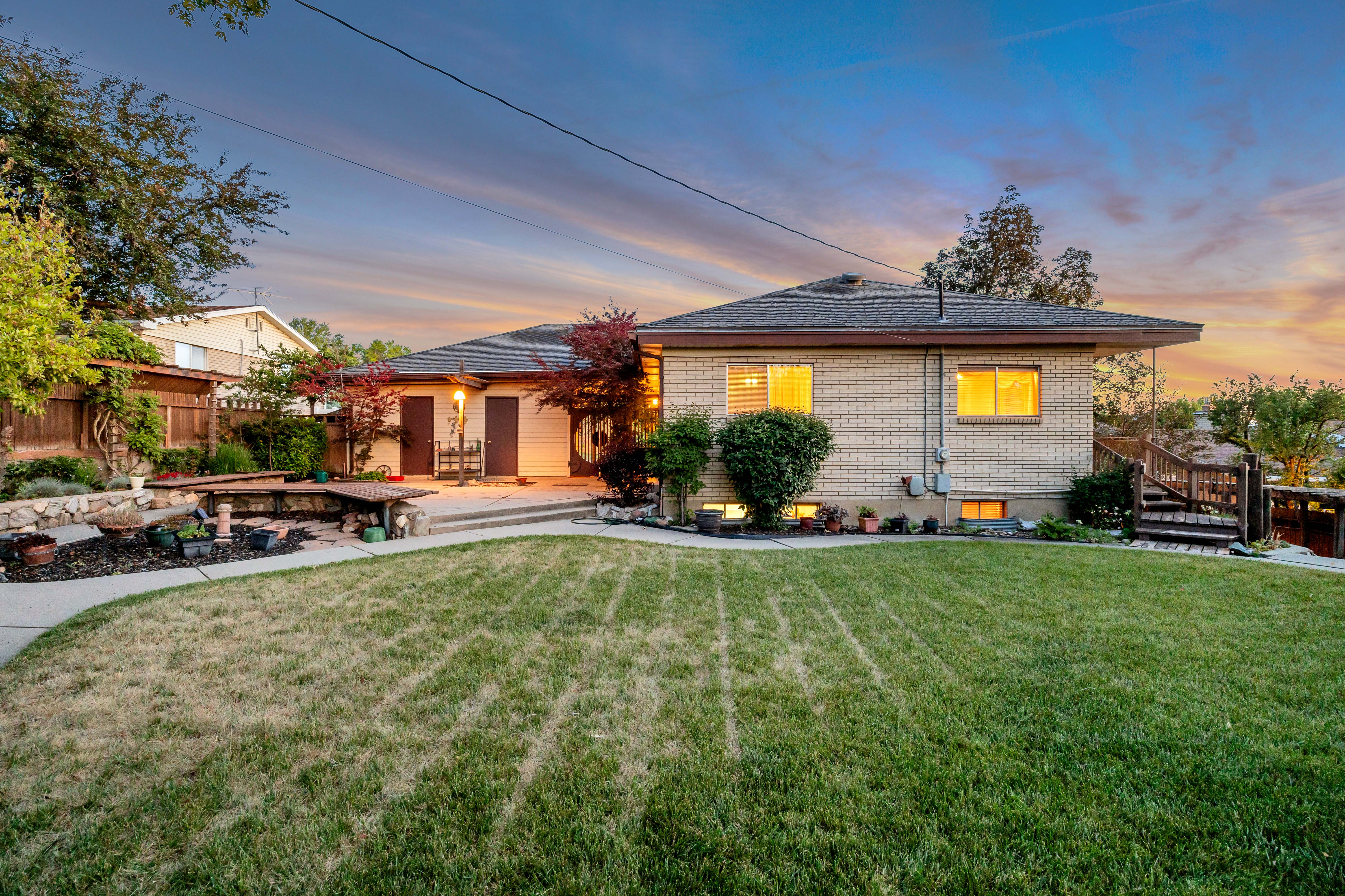 Expansive backyard featuring a manicured lawn, concrete patio space, and stone retaining walls