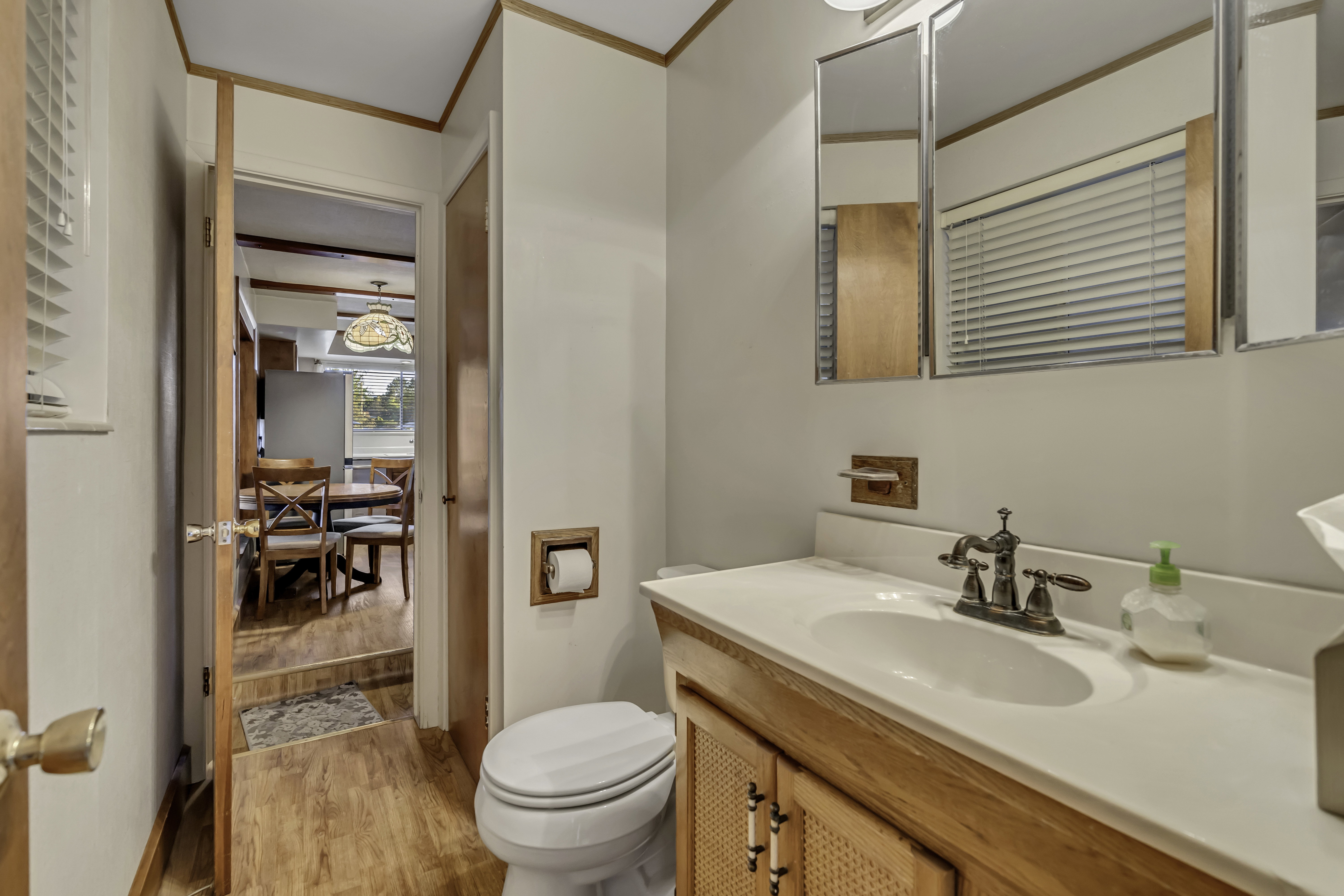 Bathroom featuring a wood-finish vanity with a white countertop and integrated sink, dual wall-mounted mirrored medicine cabinets, and wood-finish trim