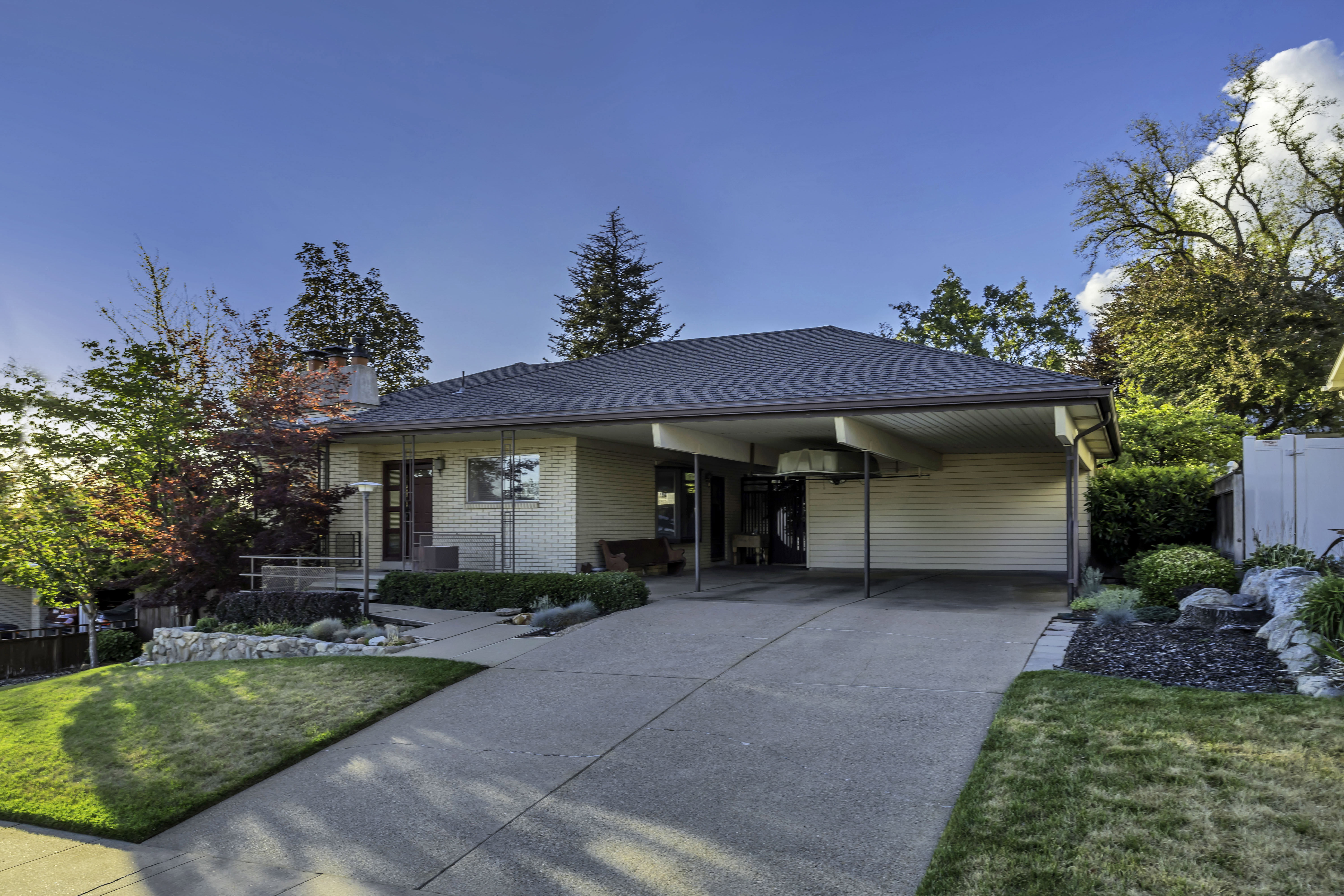 Exterior featuring a carport, a two-tone entry door, and light-colored brick siding