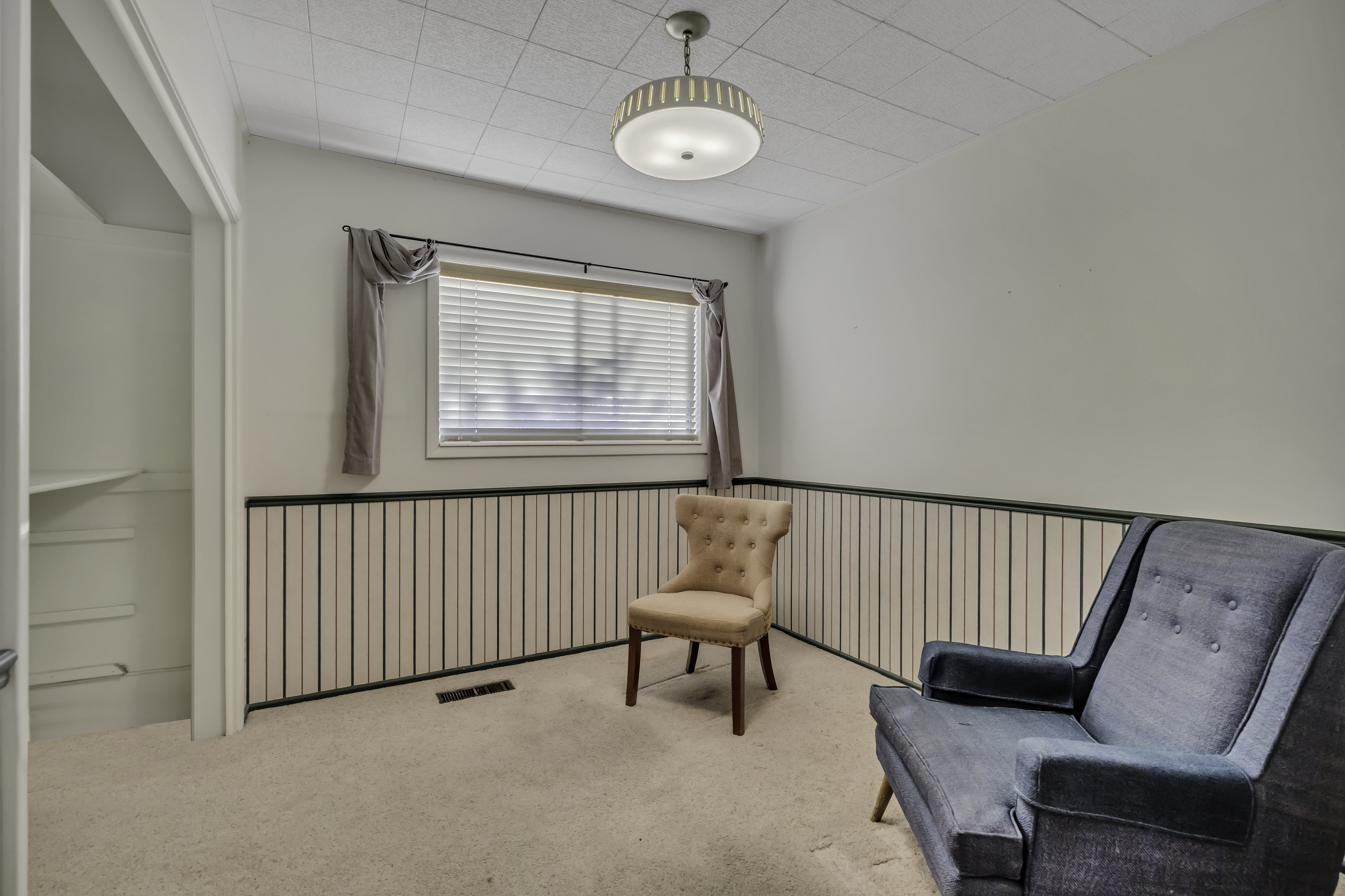 Room featuring a window with horizontal blinds, overhead flush-mount lighting, and beige carpeting