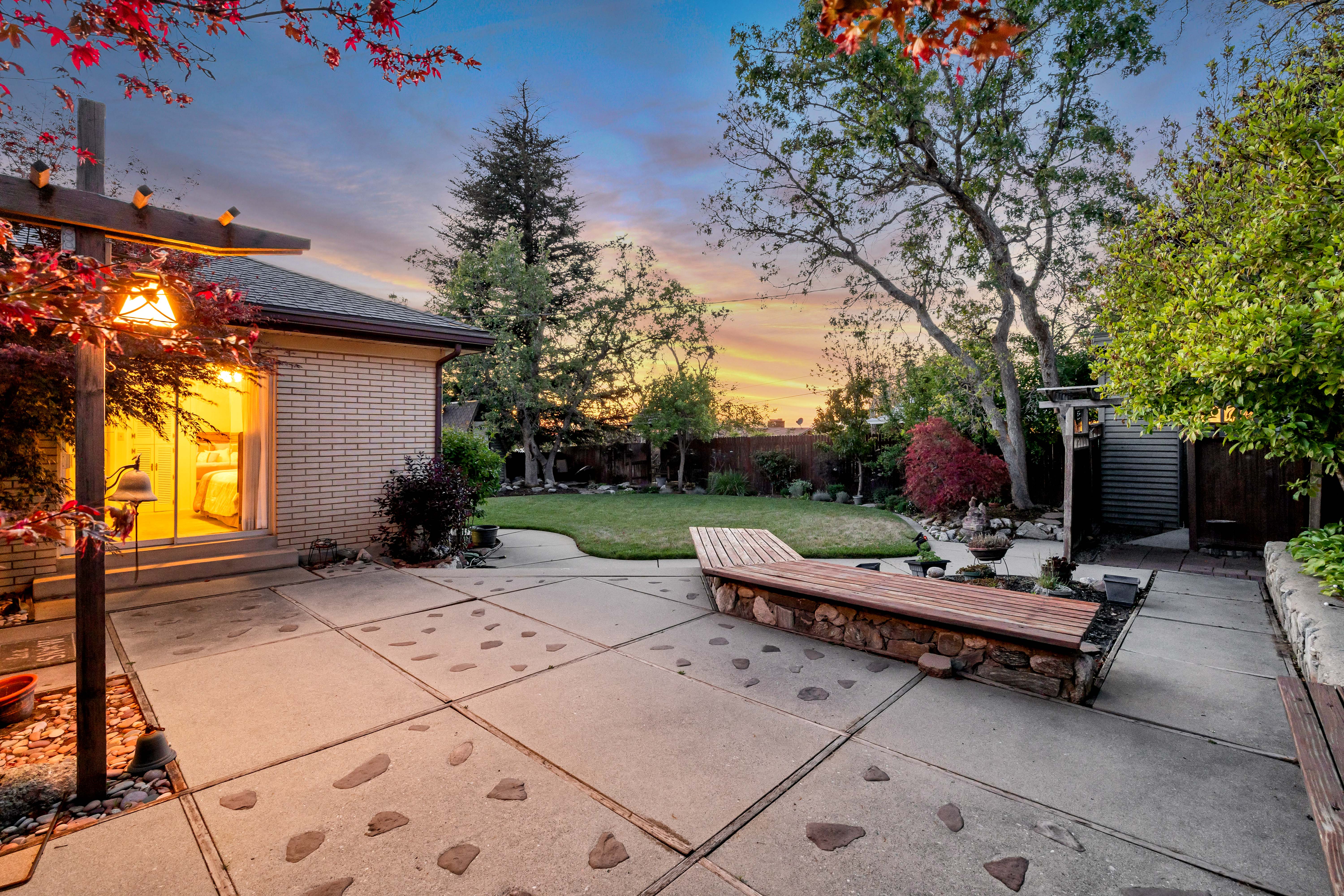 Expansive backyard featuring a large concrete patio, a built-in stone and wood bench, and a manicured lawn
