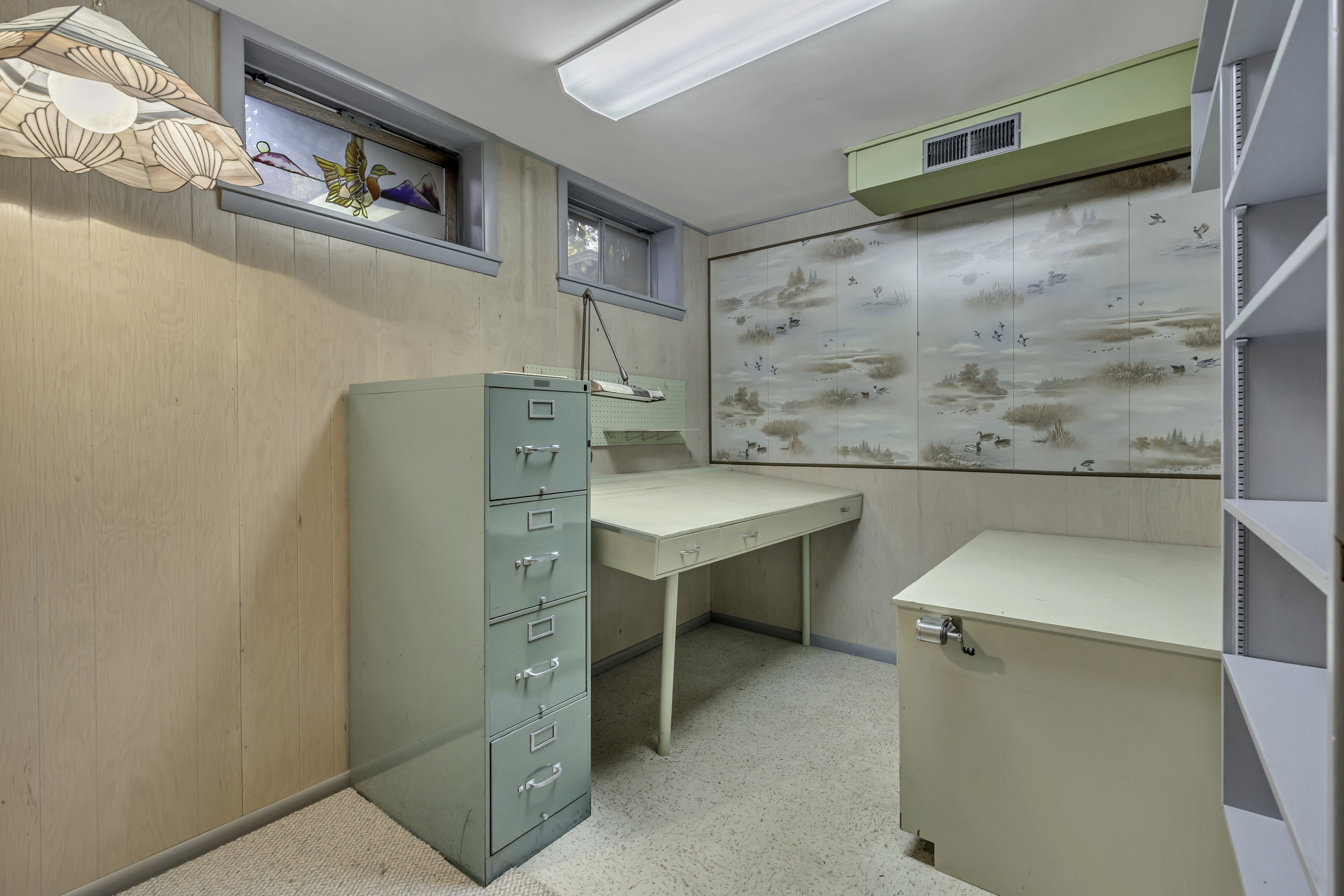 Functional room featuring two windows, built-in shelving, a built-in desk, and light-colored wall paneling