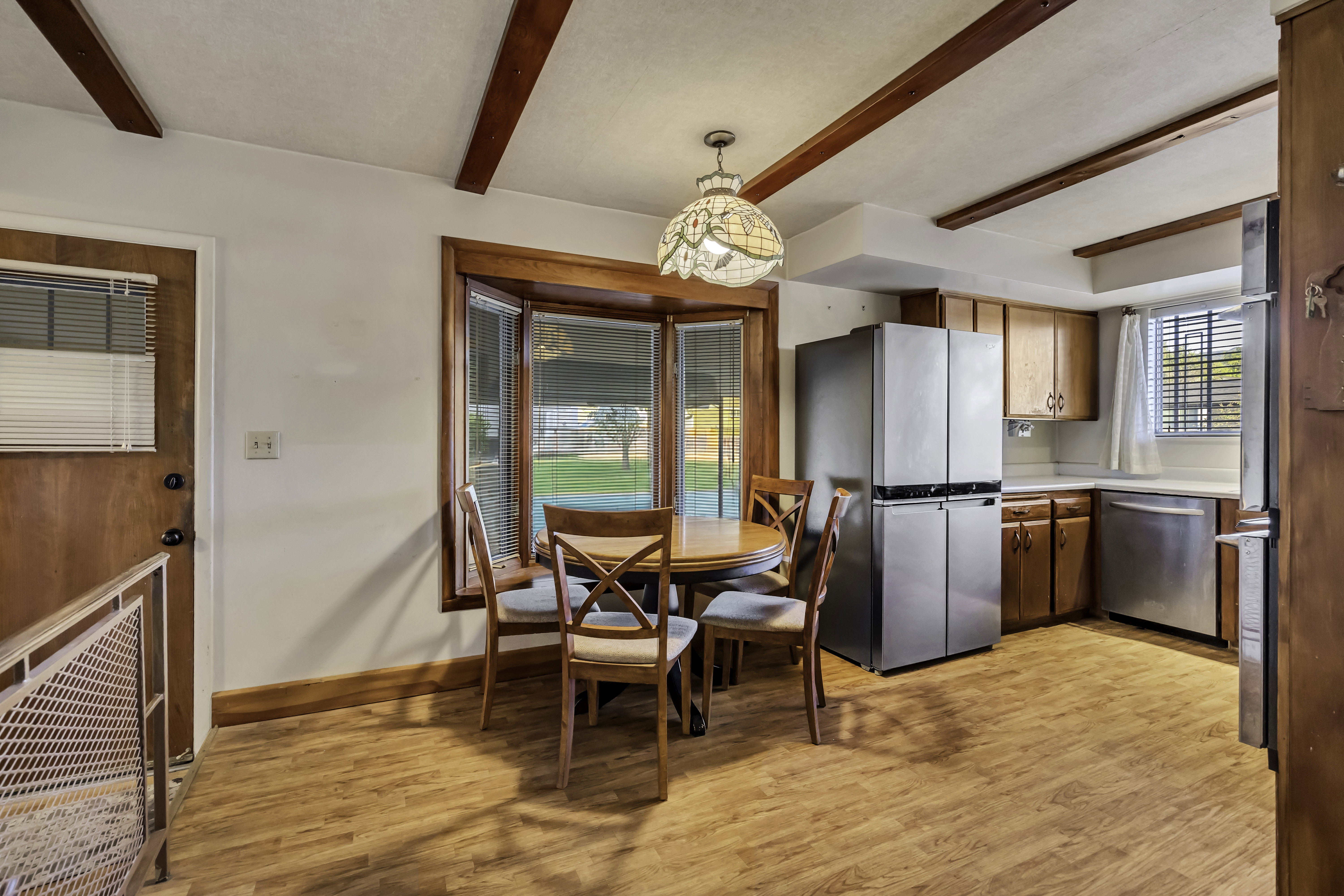 Kitchen featuring wood-finish flooring, recessed wood-beam ceiling details, and a bay window